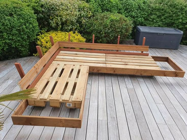 a wooden bed frame sitting on top of a wooden floor next to a potted plant