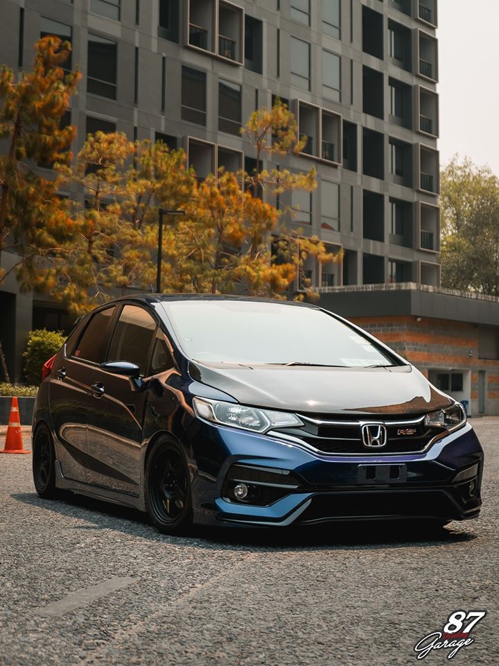 a blue car parked in front of a tall building