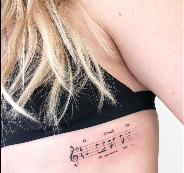 a woman's stomach with musical notes tattooed on her lower side ribcage