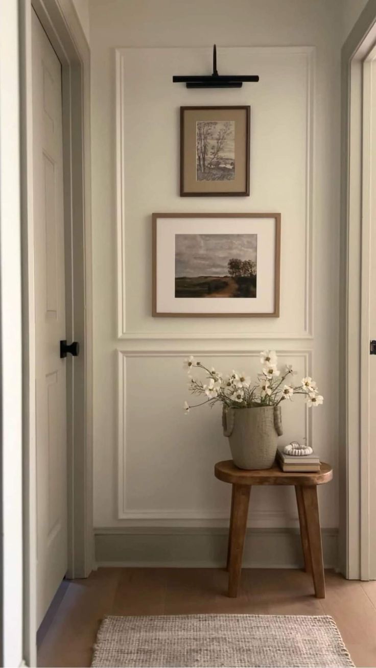 a vase with flowers sitting on top of a wooden table in front of a doorway