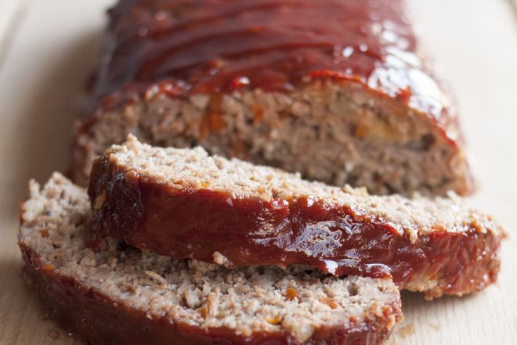 sliced meatloaf with ketchup on top and bread in the foreground