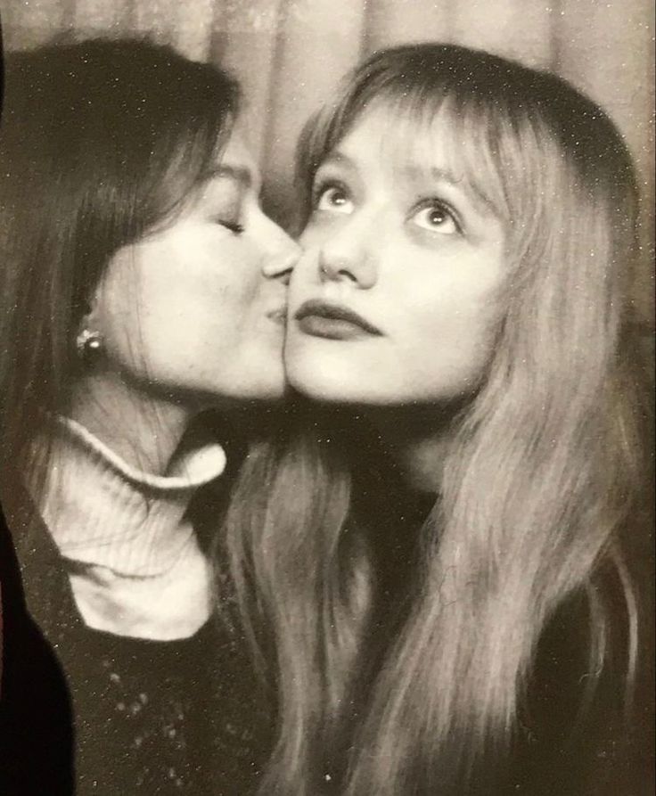 two women are kissing each other in black and white