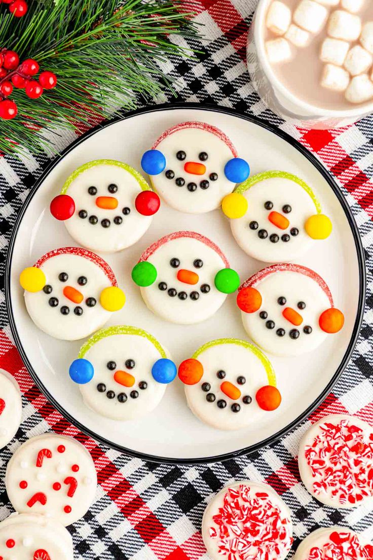 decorated cookies on a plate with marshmallows in the shape of snowmen