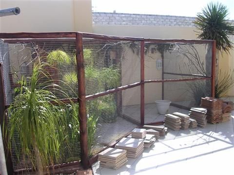 a fenced in area with some plants and boxes on the ground next to it