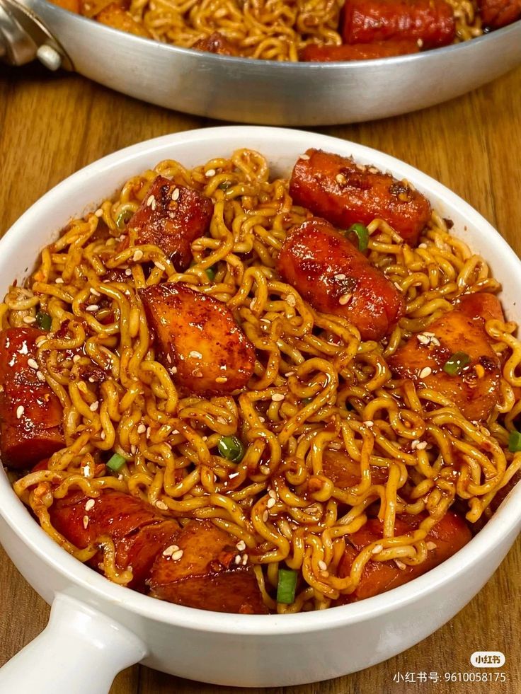 two bowls filled with noodles and meats on top of a wooden table next to each other