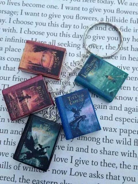 four harry potter book keychains sitting on top of an open book with the words,