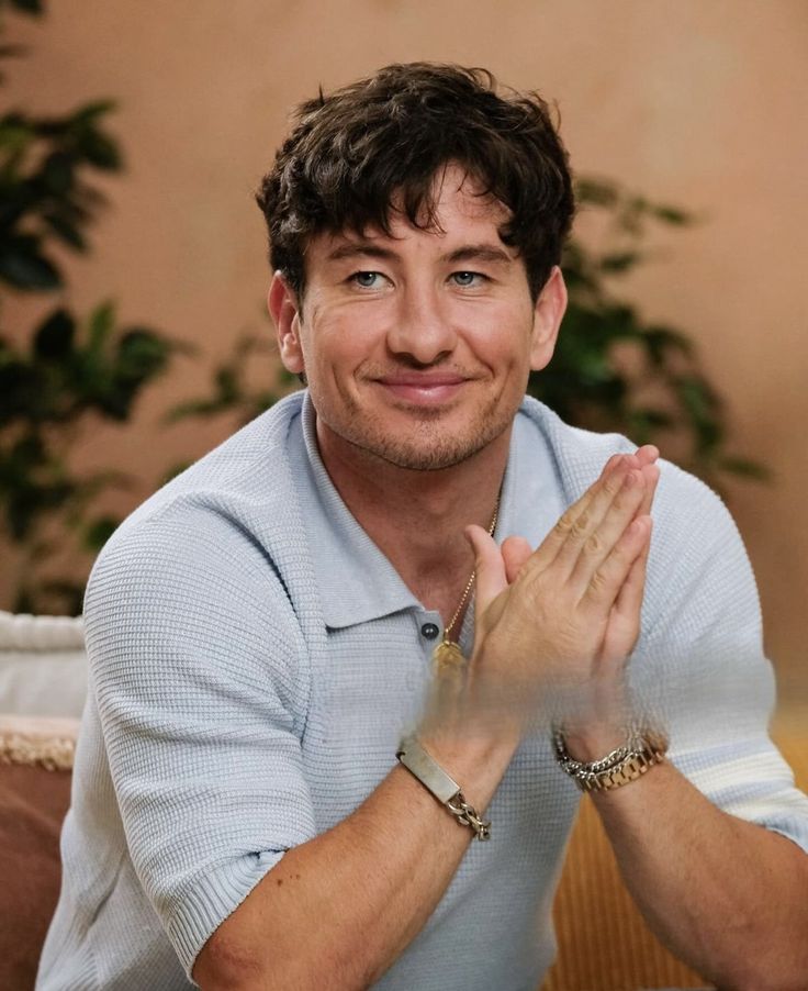 a man sitting on top of a couch with his hands together