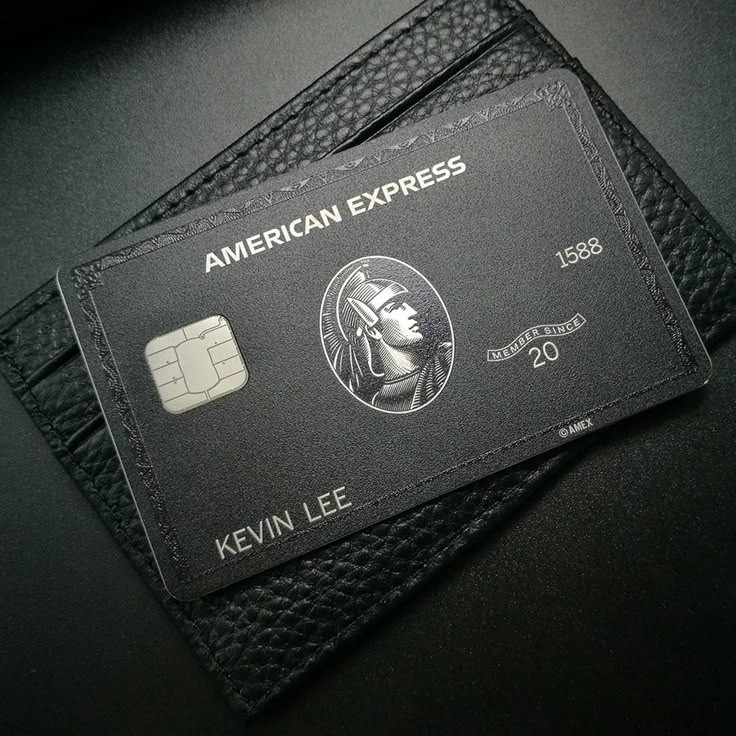 an american express credit card sitting on top of a black leather wallet with the name, kevin lee