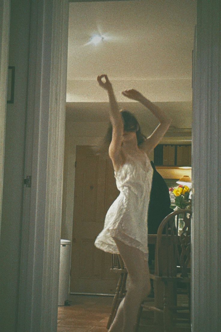 a woman in a white dress is standing on the floor with her arms raised up