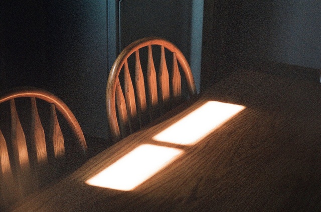 a table with two chairs and a light shining on the top one in front of it