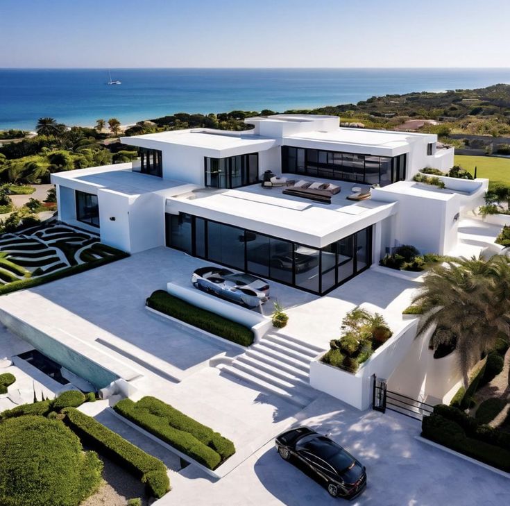 an aerial view of a modern house with cars parked in the driveway and landscaping around it