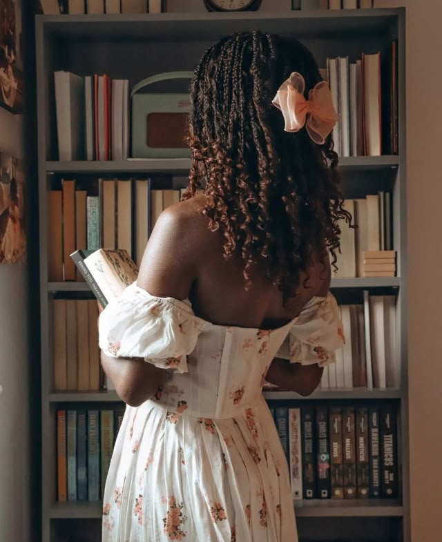 a woman standing in front of a bookshelf with her back to the camera