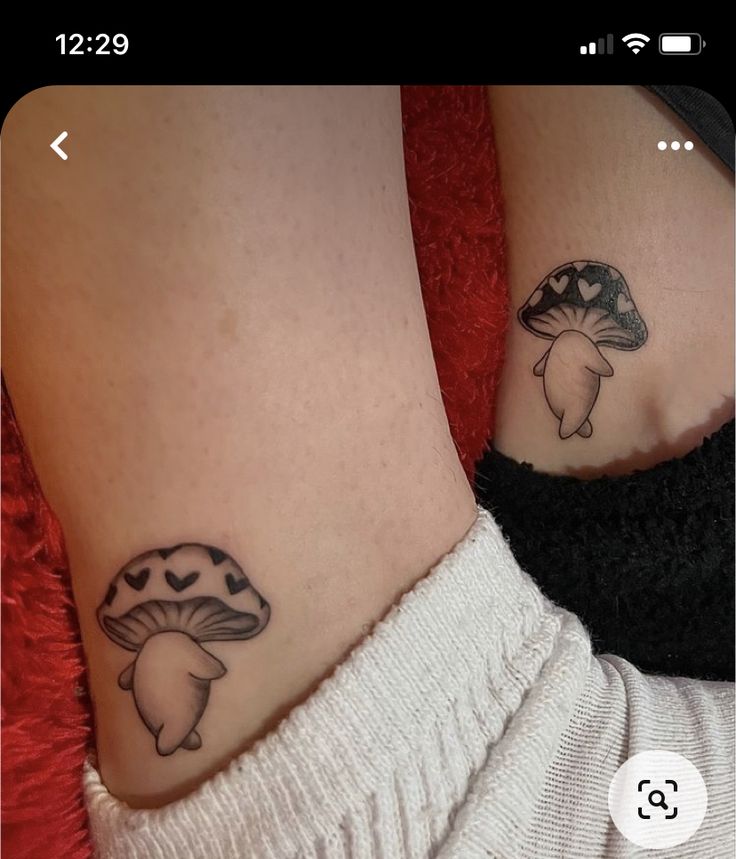 two people with matching tattoos on their feet, one has a mushroom and the other has a heart