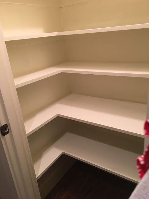 an empty closet with white shelves and red flowers on the door handle, in front of a wooden floor