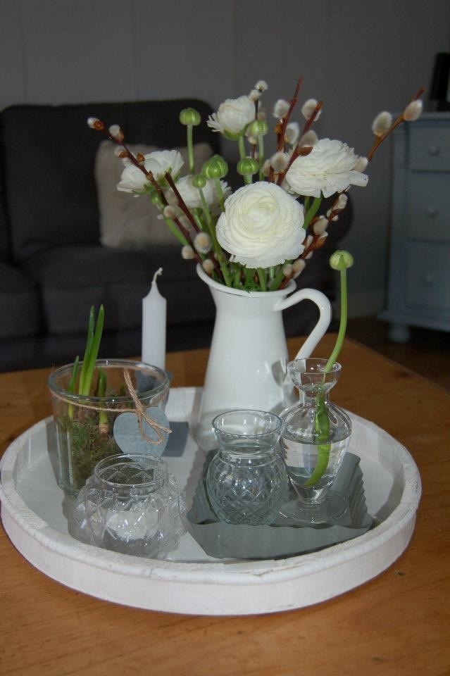 a white pitcher and glasses on a tray with flowers in it, sitting on a table