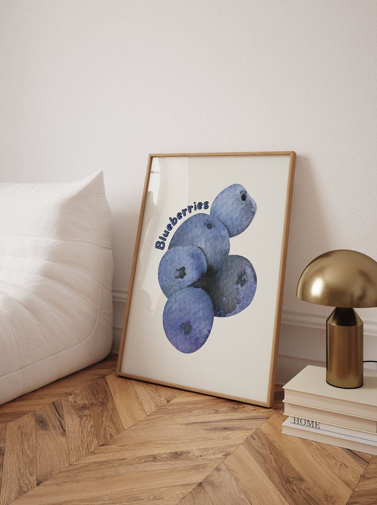 there is a picture frame with blueberries on it next to a lamp and books