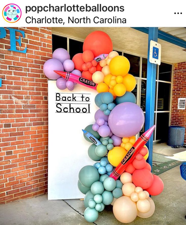 a bunch of balloons that are in the shape of a school building with a back to school sign