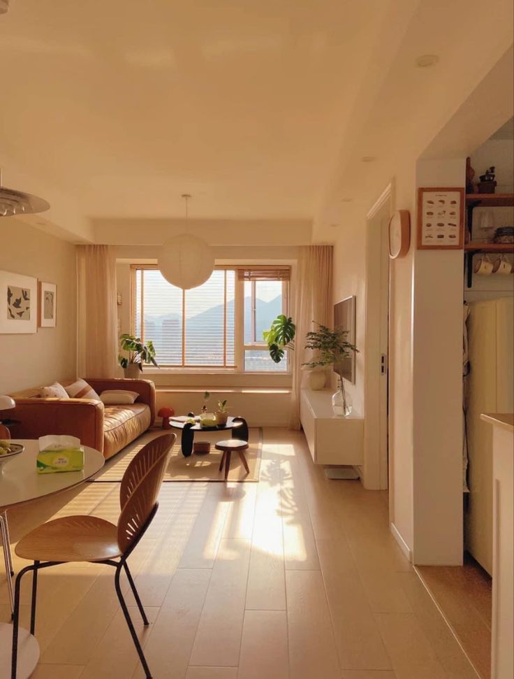 a living room filled with furniture next to a kitchen and dining room table in front of a window