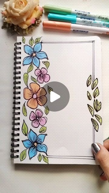 someone is drawing flowers on a notebook with markers and crayon pencils next to it