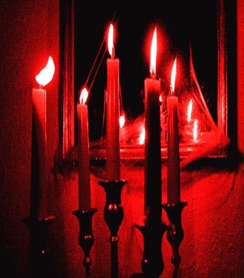 candles are lit in front of a mirror with red light coming from the candle holders