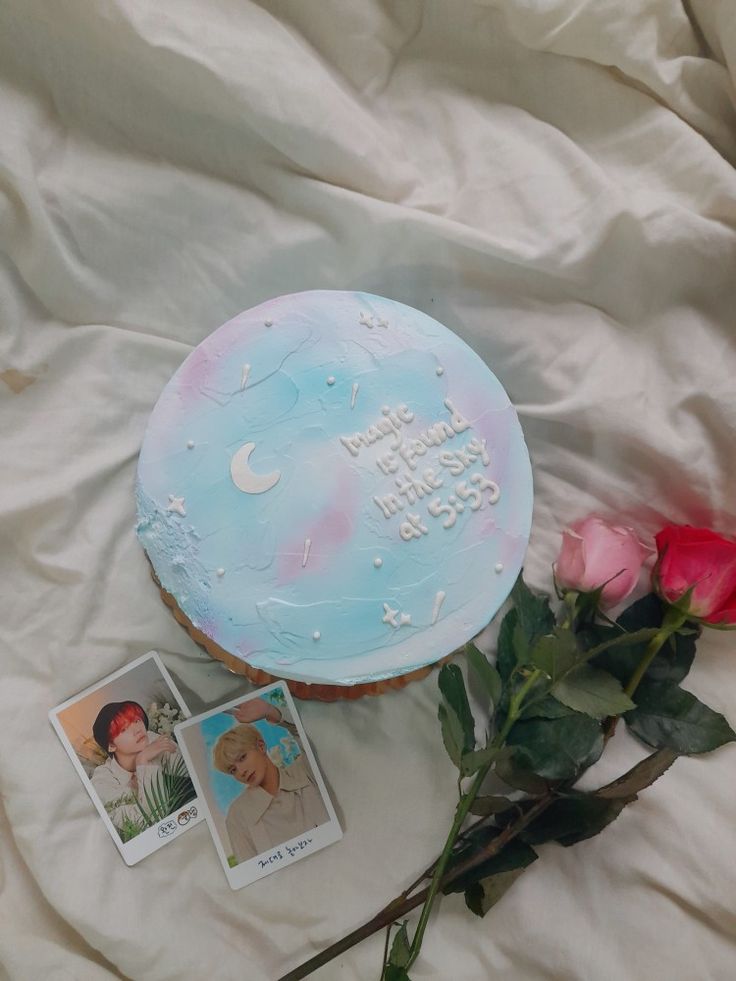 a birthday cake and some flowers on a white sheet with two photos next to it