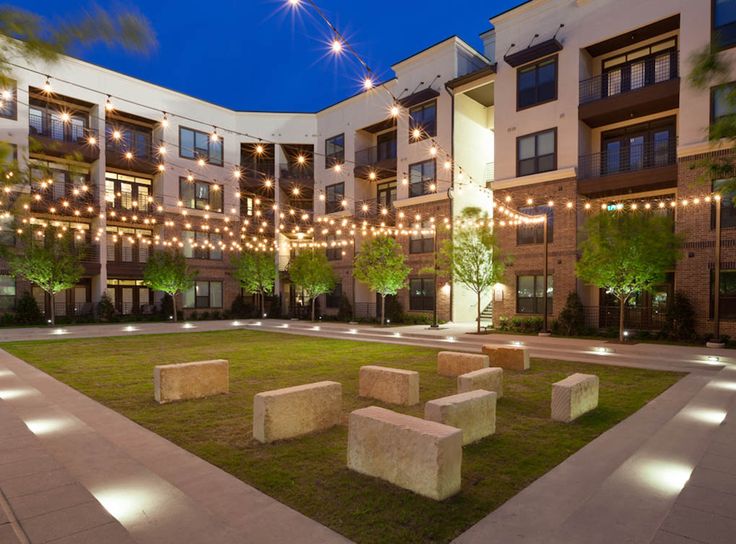 an apartment building with lights strung over the courtyard and grass area in front of it