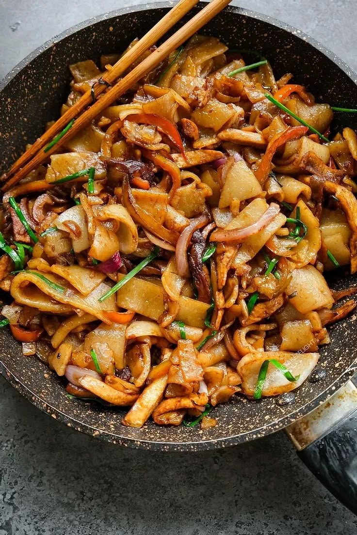 stir fry with vegetables and chopsticks in a skillet on a gray surface