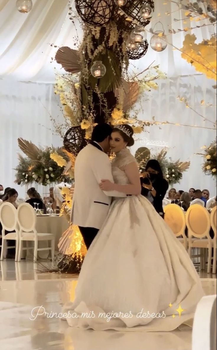 a bride and groom standing in front of a chandelier at their wedding reception