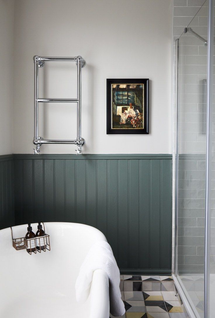 a bath tub sitting next to a shower with a painting on the wall above it