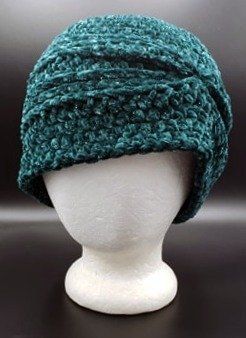 a white mannequin head wearing a green knitted hat