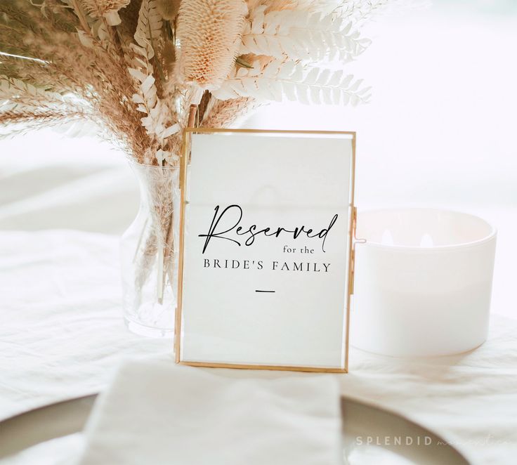 a table with a white candle and a sign on it that says reserved for the bride's family