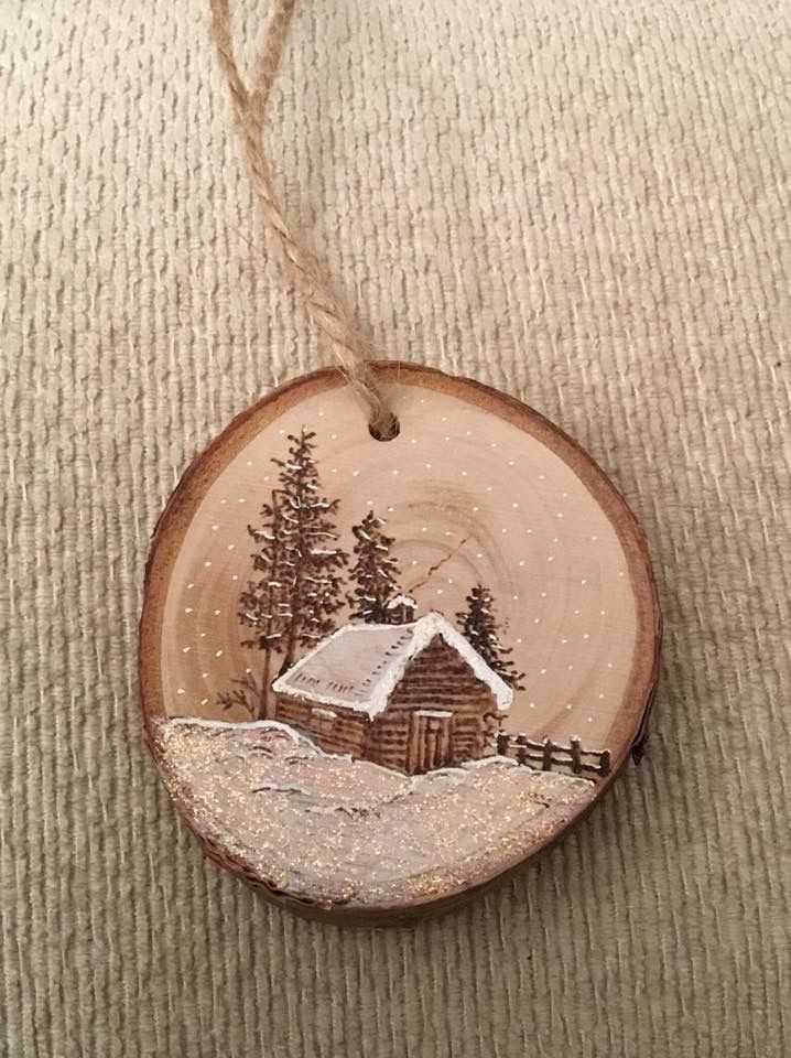 a wooden ornament with a cabin in the woods on it's side