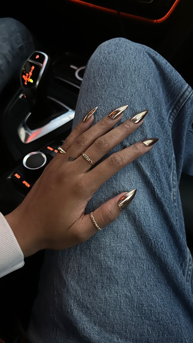 Gold chrome gel-x medium stiletto nails on a black girl’s hand while wearing gold jewelry and rings Chrome Nail Colors, Black Chrome Nails, Gold Chrome Nails, Gold Acrylic Nails, Chrome Nails Designs, Metallic Nails, Dark Nails, Prom Nails, Minimalist Nails