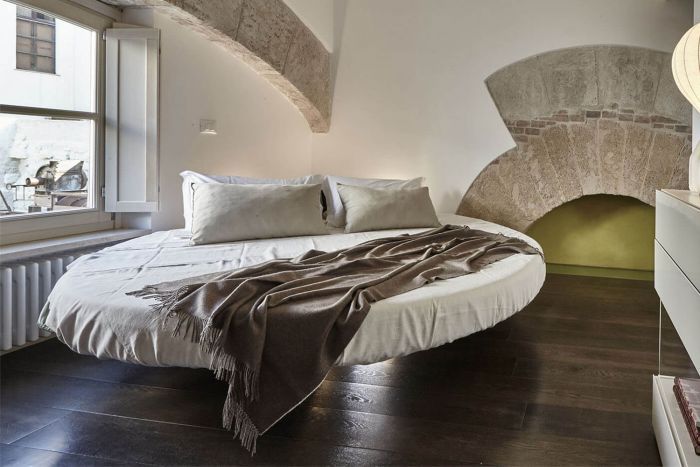 a bed sitting in the middle of a bedroom next to a window with an arched ceiling