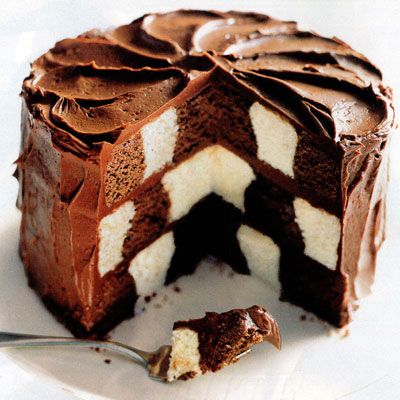 a chocolate cake with white and brown icing on a plate next to a fork