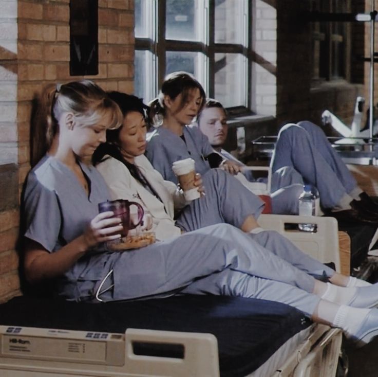 a group of women in scrubs sitting on top of medical beds and holding drinks