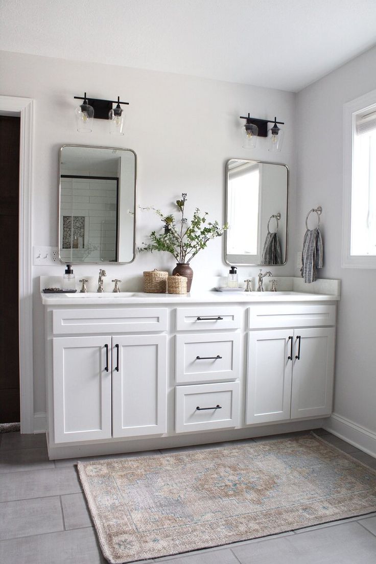 a bathroom with two sinks, mirrors and a rug on the floor in front of it