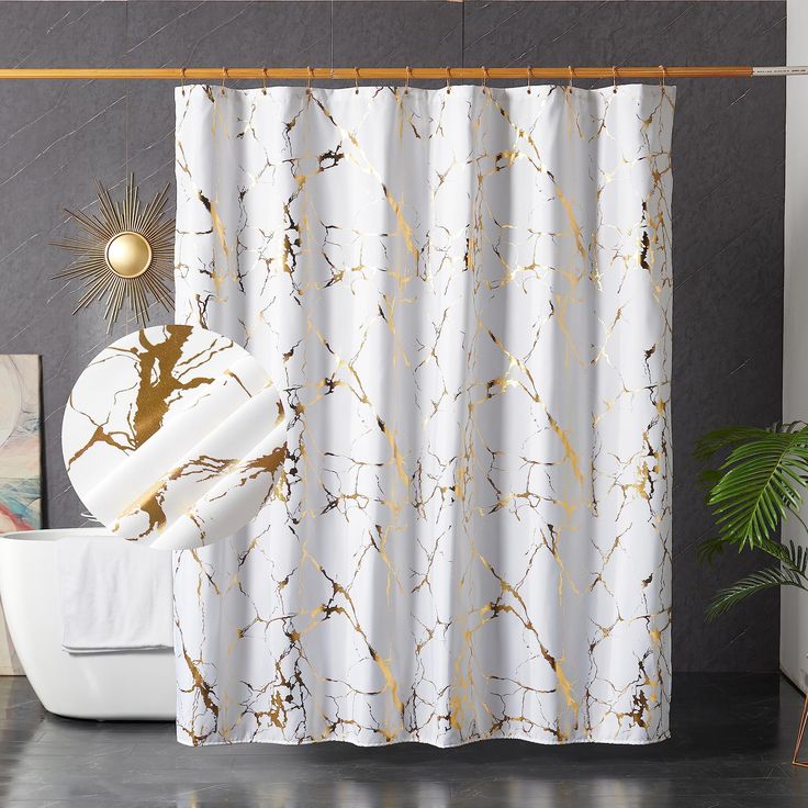 a white shower curtain with gold paint splattered on it, next to a potted plant