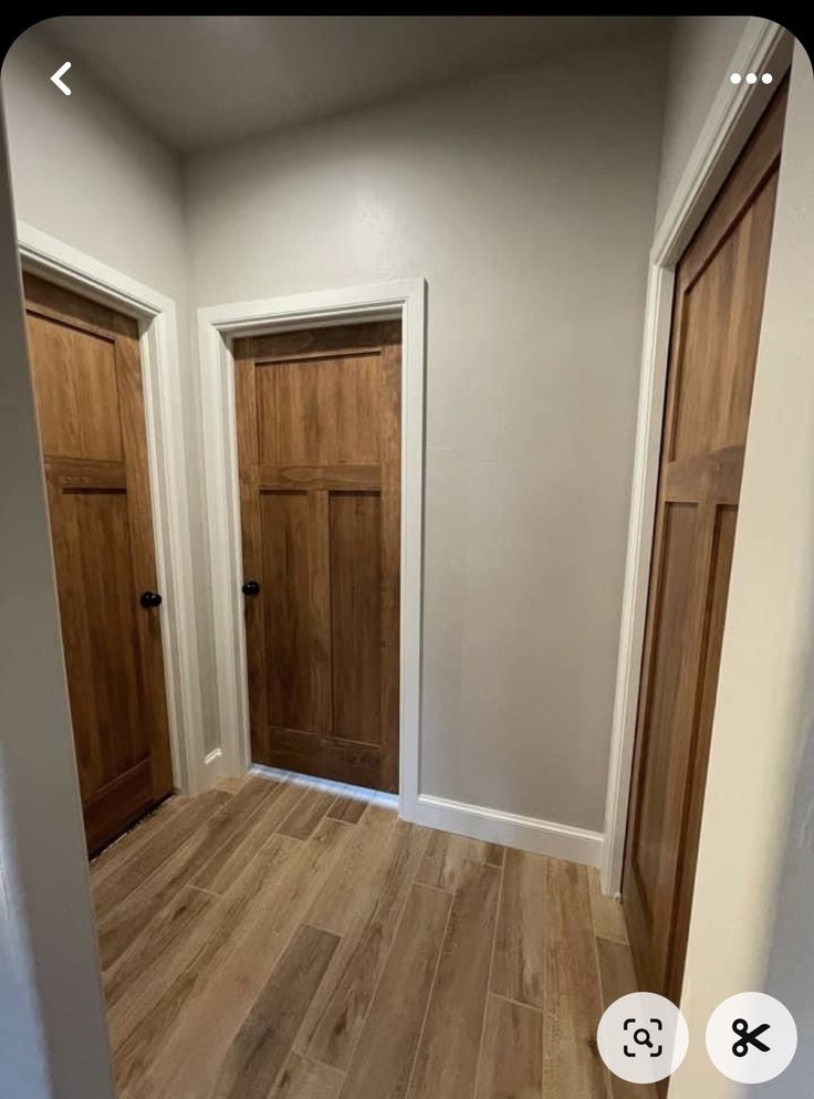 an empty room with two wooden doors and hard wood flooring on the side walk