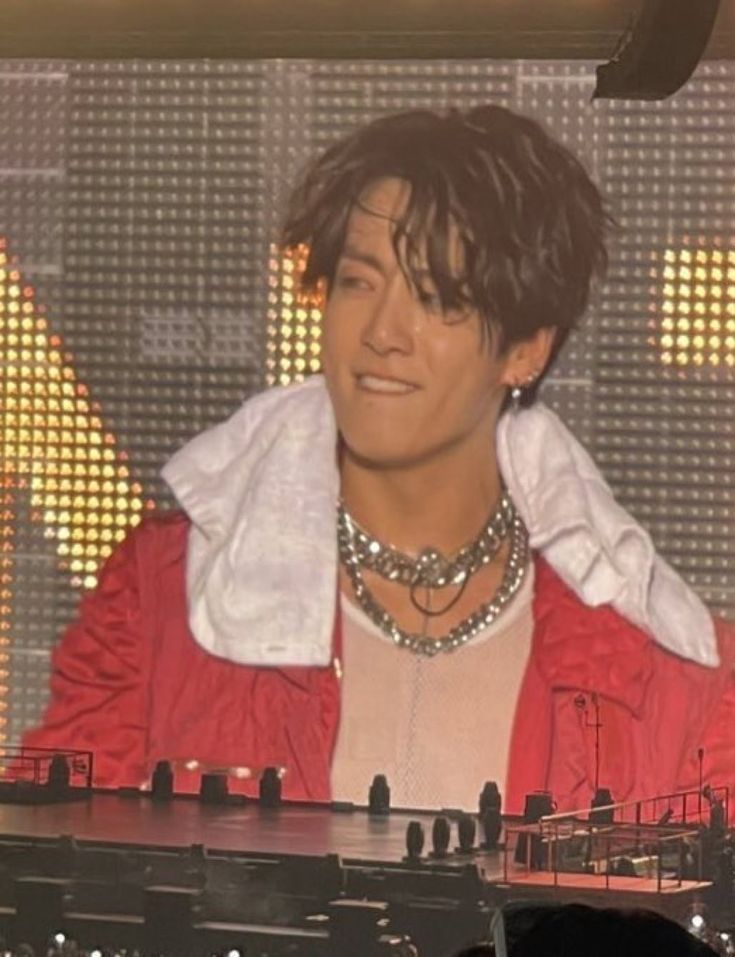 the man is wearing a red jacket and silver necklace