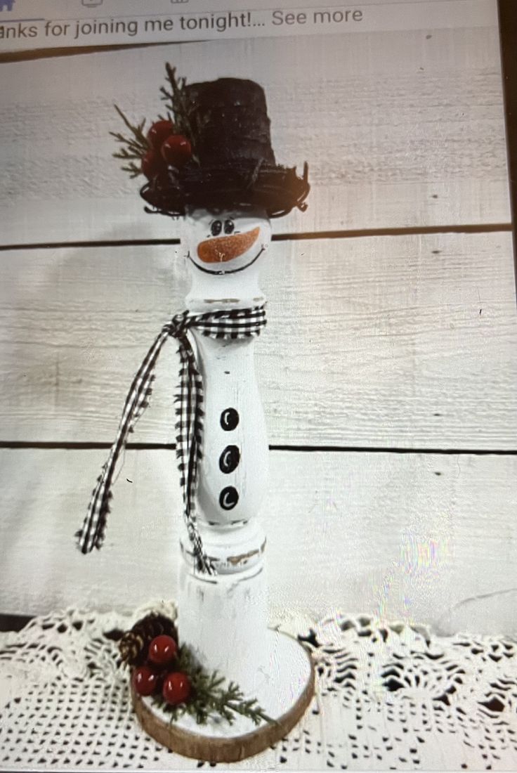 a snowman with a hat and scarf on it's head sitting on a doily