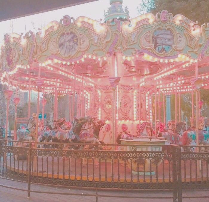 an old fashioned merry go round with lights on it's sides and horses at the top