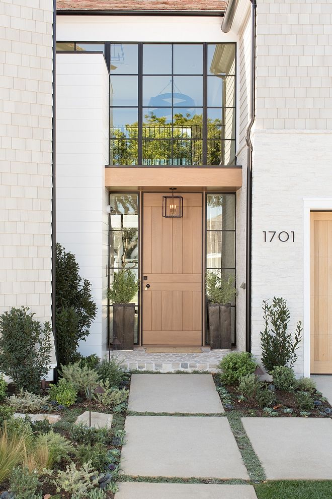 the front entrance to a house with plants and shrubs