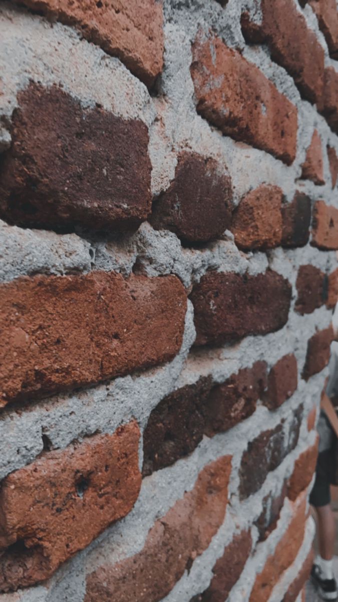 a person standing next to a brick wall