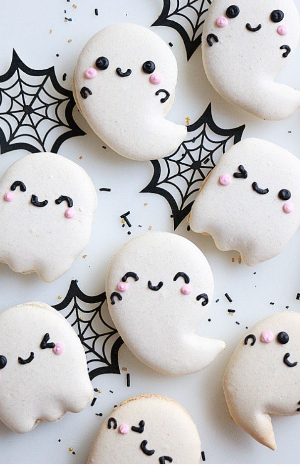 halloween cookies decorated with white icing and black sprinkles are arranged in the shape of ghost faces