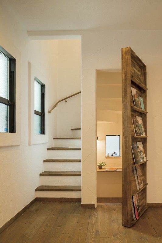 an empty room with stairs and bookshelf in the corner next to a window