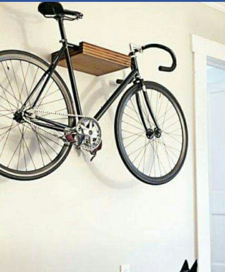 a dog laying on the floor in front of a bicycle mounted to a wall with a bike hanging from it's side