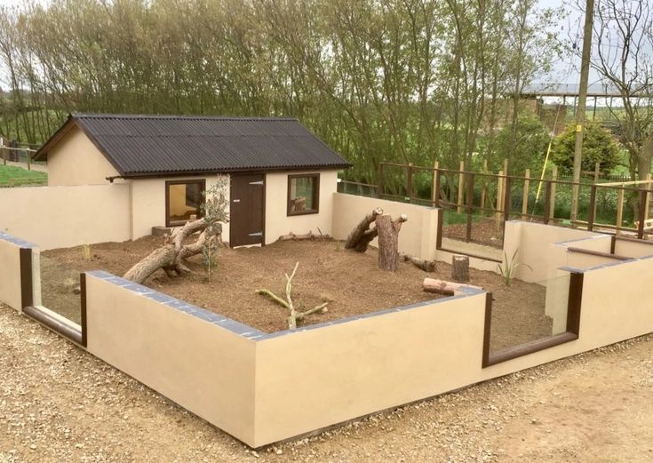 a small house made out of cinder blocks with trees in the back ground and fence around it