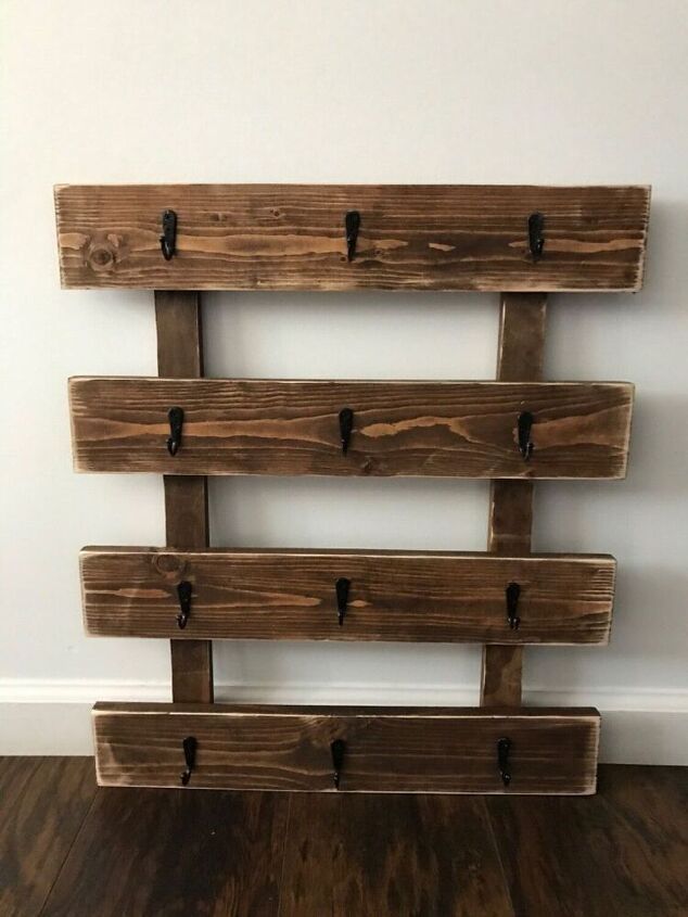 a wall mounted shelf made out of wooden planks with hooks on the top and bottom