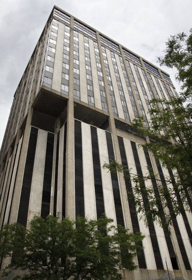 a very tall building with lots of windows on it's sides and trees in the foreground